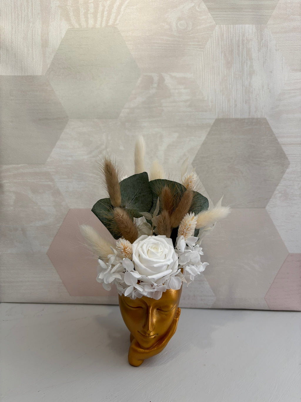 Composition florale avec une fleur d’or de Rêves En Fleurs, présentant des pétales dorés et des feuilles vertes.