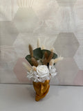 Composition florale avec une fleur d’or de Rêves En Fleurs, présentant des pétales dorés et des feuilles vertes.