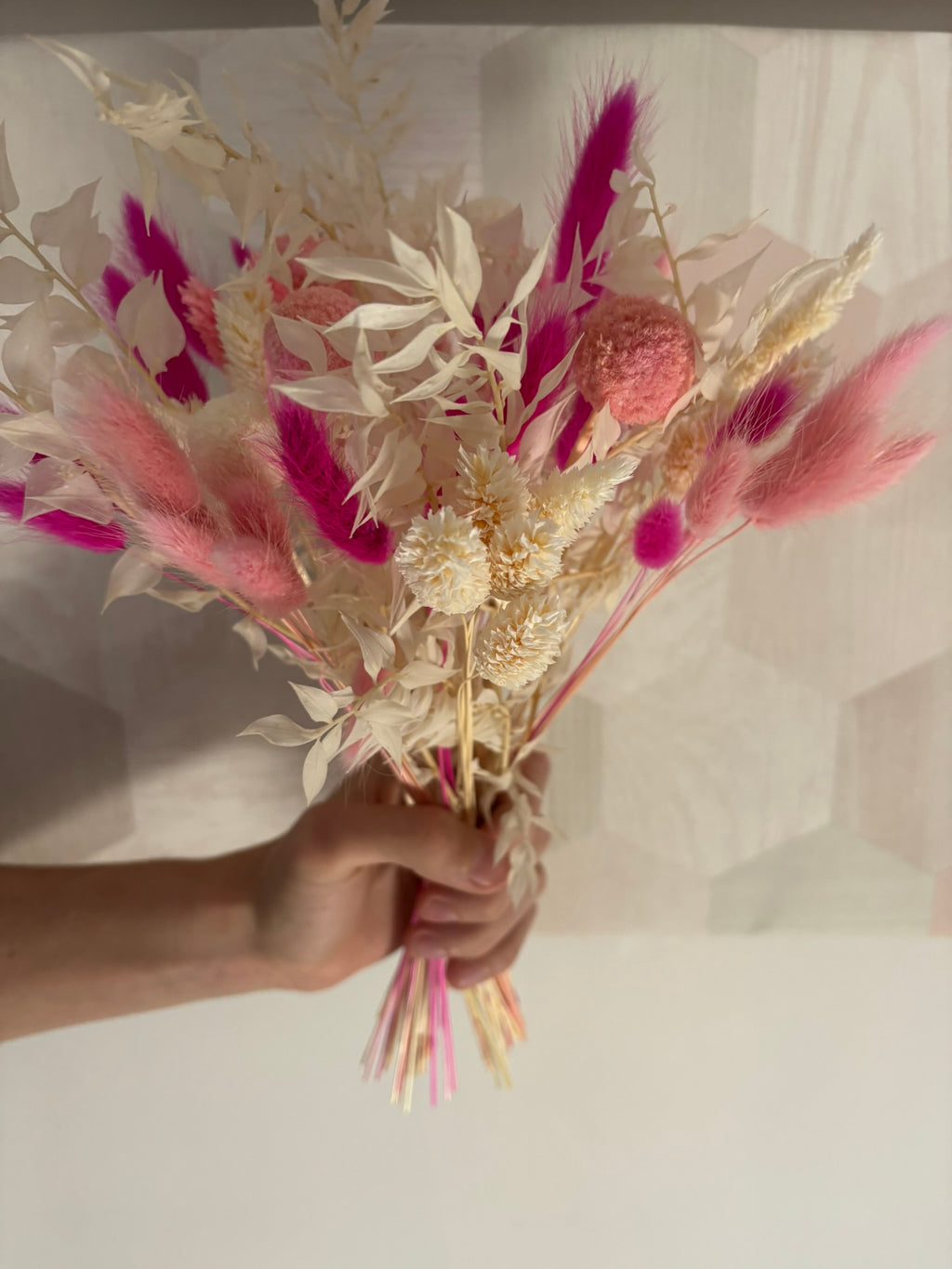 Bouquet fuchsia Rêves En Fleurs avec des fleurs roses vives et des feuilles vertes, présenté dans un arrangement élégant.
