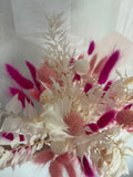 Bouquet de fleurs fuchsia Rêves En Fleurs avec des fleurs roses vives et des feuillages verts, présenté dans un arrangement élégant.