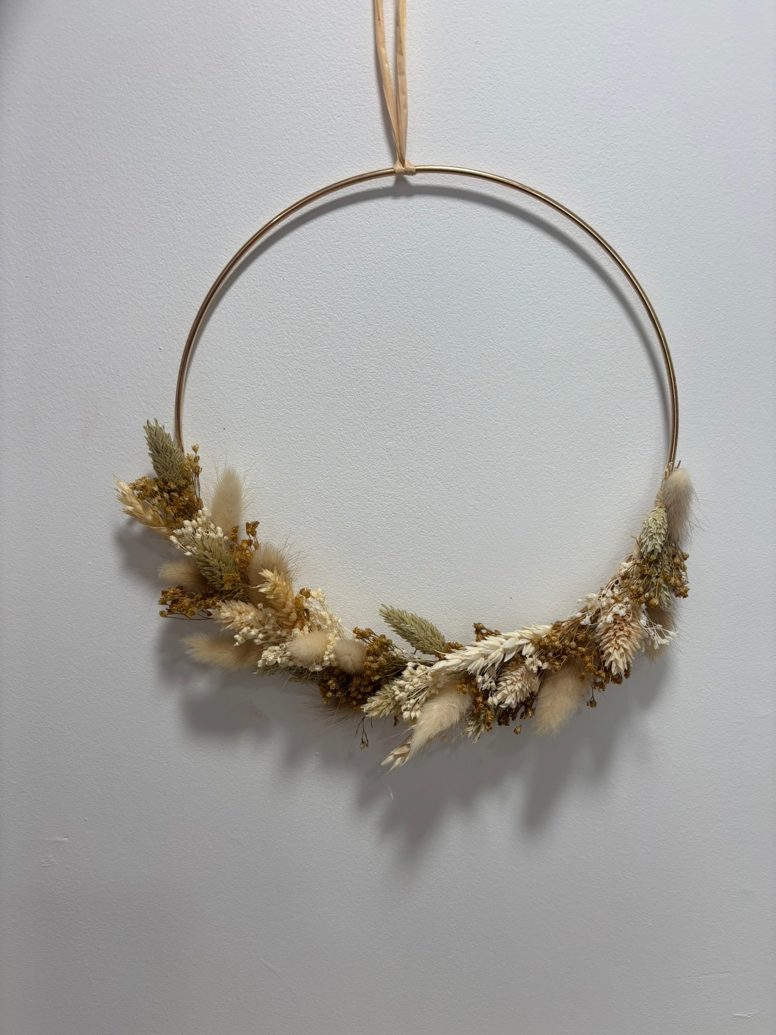 Couronne végétale Éclat de la marque Rêves En Fleurs posée sur une surface naturelle, avec des fleurs colorées et des feuillages.