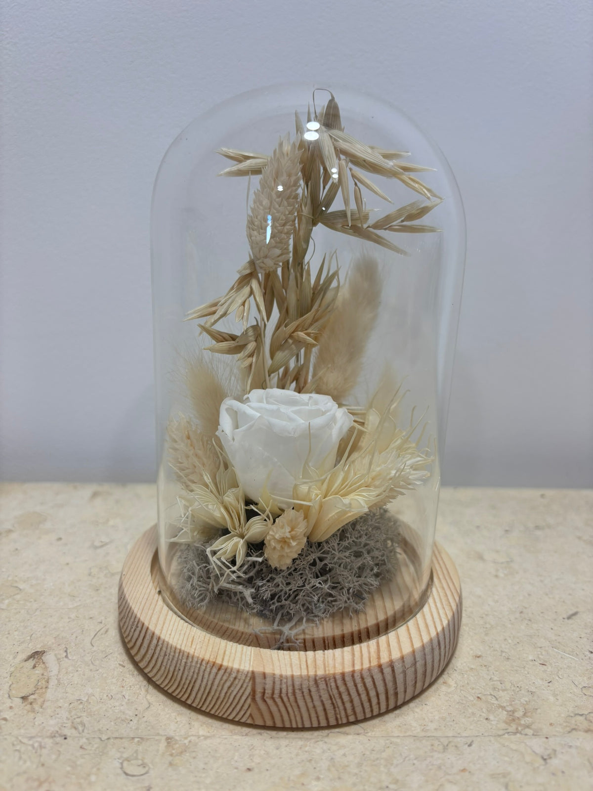 Cloche blanche élégante de la marque Rêves En Fleurs, en verre transparent avec base en bois naturel.