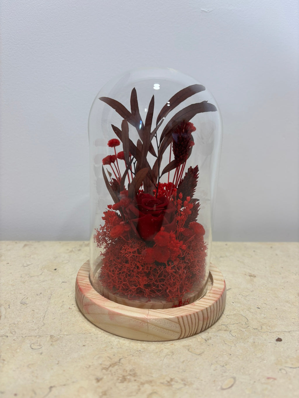 Cloche rouge de Rêves En Fleurs en verre transparent, avec une base élégante et une finition brillante.