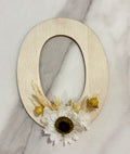 Barrette lettre Rêves En Fleurs en métal doré, décorée de motifs floraux, portée comme accessoire de cheveux élégante.
