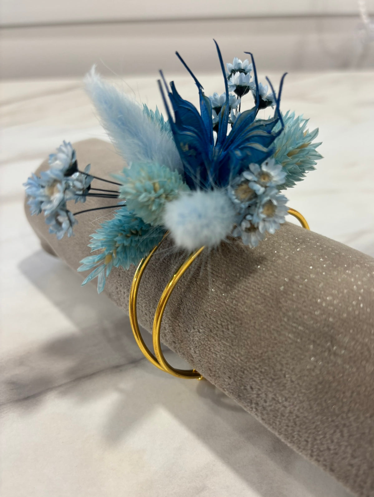 Bracelet bleu en tissu de la marque Rêves En Fleurs avec détails délicats, porté sur un poignet.