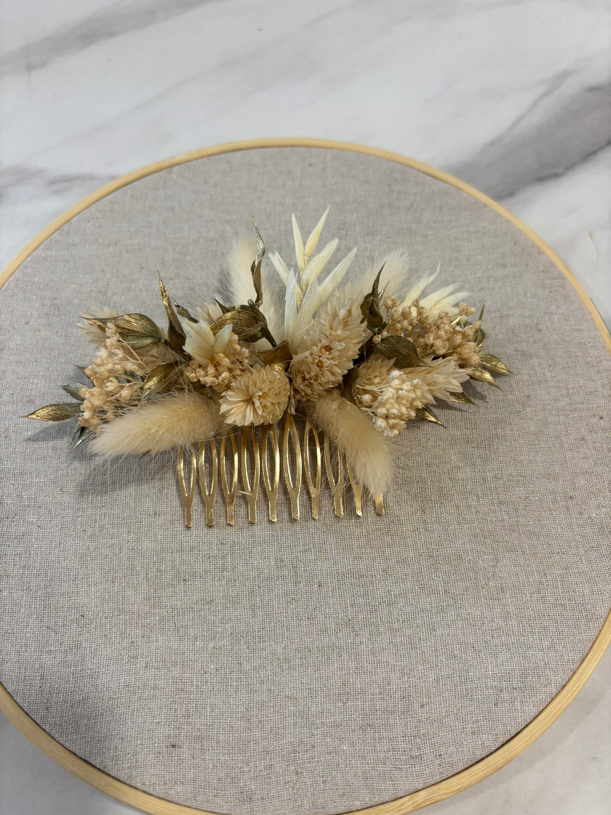 Peigne blanc et doré Rêves En Fleurs en plastique élégant pour cheveux, avec détails dorés.
