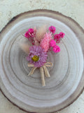 Boutonnière en rose, conçue par Rêves En Fleurs, avec boucle d'oreille élégante assortie, visible dans l'image.