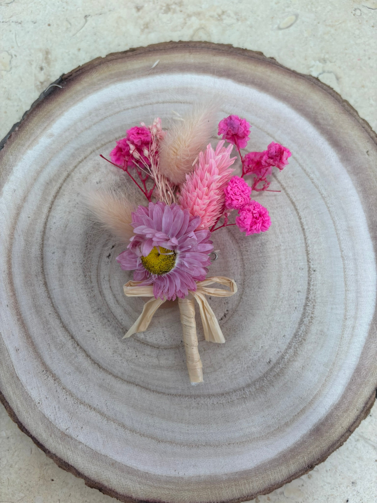 Boutonnière en rose, conçue par Rêves En Fleurs, avec boucle d'oreille élégante assortie, visible dans l'image.
