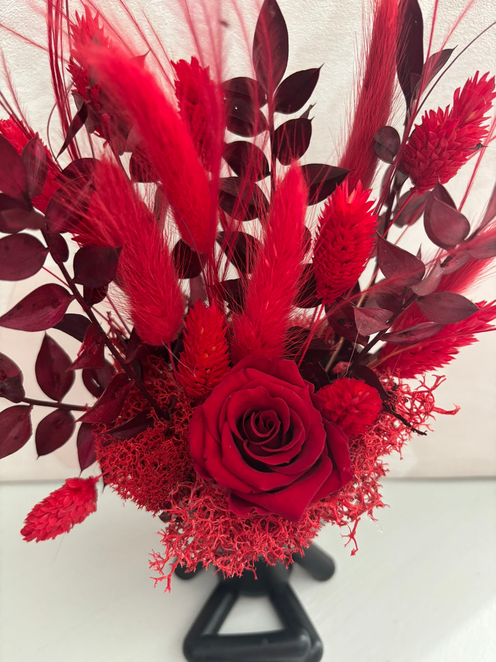 Composition florale rouge de Rêves En Fleurs avec des fleurs rouges vibrantes et des feuilles vertes naturelles.